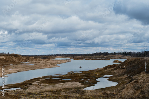 Fototapeta Naklejka Na Ścianę i Meble -  Artificially dug pits and ponds or lakes. Beautiful view of sand dunes and quarries with water in cloudy sunny weather in spring. Landscapes of Russia Moscow region.