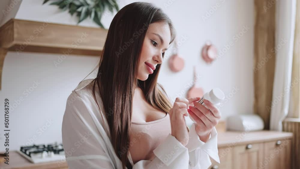 Pregnant lady reads dosing on bottle with vitamin supplement Pregnant lady reads dosing on bottle with vitamin supplement