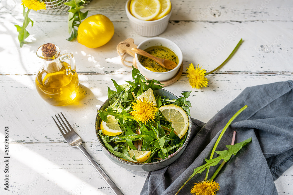 Dandelion salad with olive oil, lemon juice and spices on white wooden table with grey background Dandelion salad with olive oil, lemon juice and spices on white wooden table with grey background