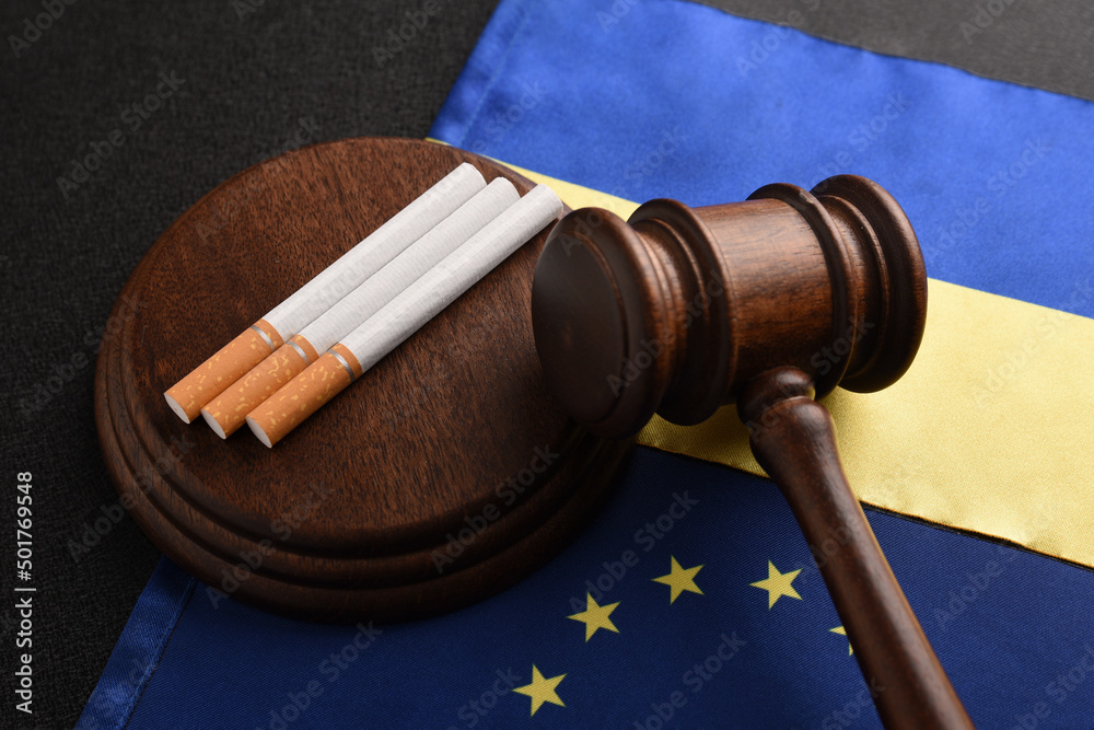 Flag of Ukraine with flag of European Union, cigarettes and Judge gavel. Illegal transport of tobacco products. Smuggling between Ukraine and EU.