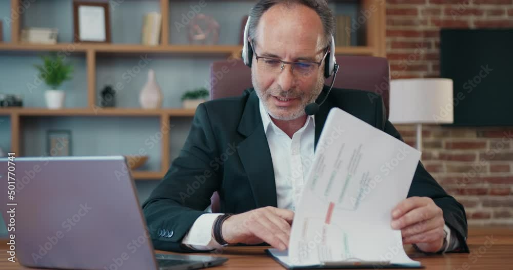 Middle eastern boss look at resume paper and having work confrence video call. Businessman expert talk to teammates online explain amend document details. Middle eastern boss look at resume paper and having work confrence video call. Businessman expert talk to teammates online explain amend document details.