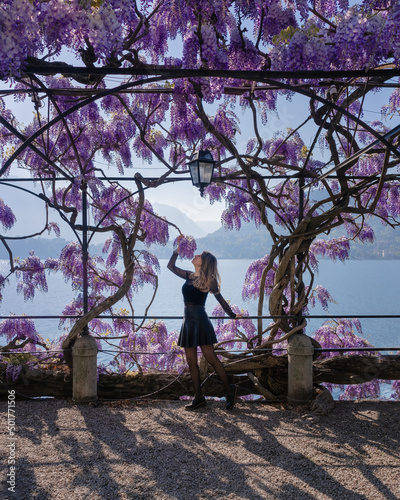 Girl smelling wisteria flowers on Lake Como shore during the spring seaason. photo