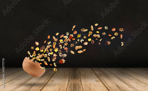 Flying nuts-The mix nuts and raisins in a wooden bowl-black background-Wooden desk