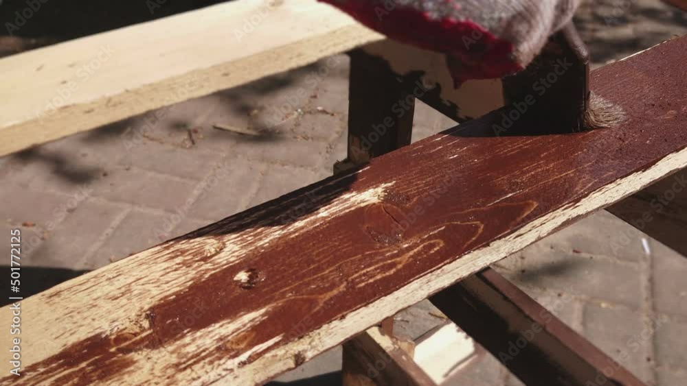 Painting wood in the home garden. Wooden element protection with paintbrush in hand. Painting wood in the home garden. Wooden element protection with paintbrush in hand.