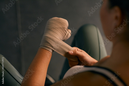 High angle shot of professional boxer wrapping her hands with elastic bandage