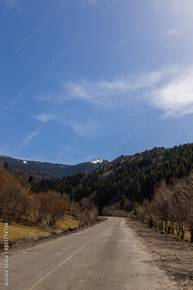 Road, mountains and blue sky at background.