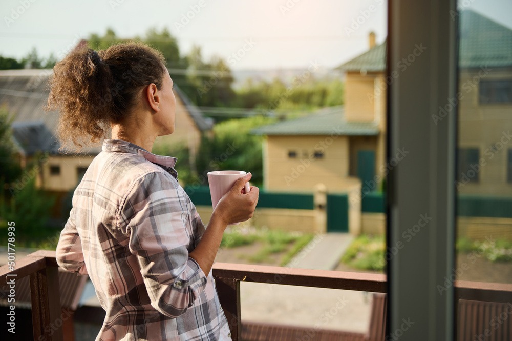Rear view of woman drinking coffee on the balcony of her country house
