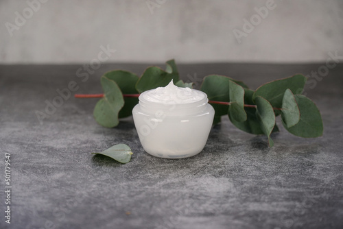  Cosmetics products branding mockup. Jar of moisturizer cream on grey background with eucalyptus leaves. Organic herbal beauty products.                 