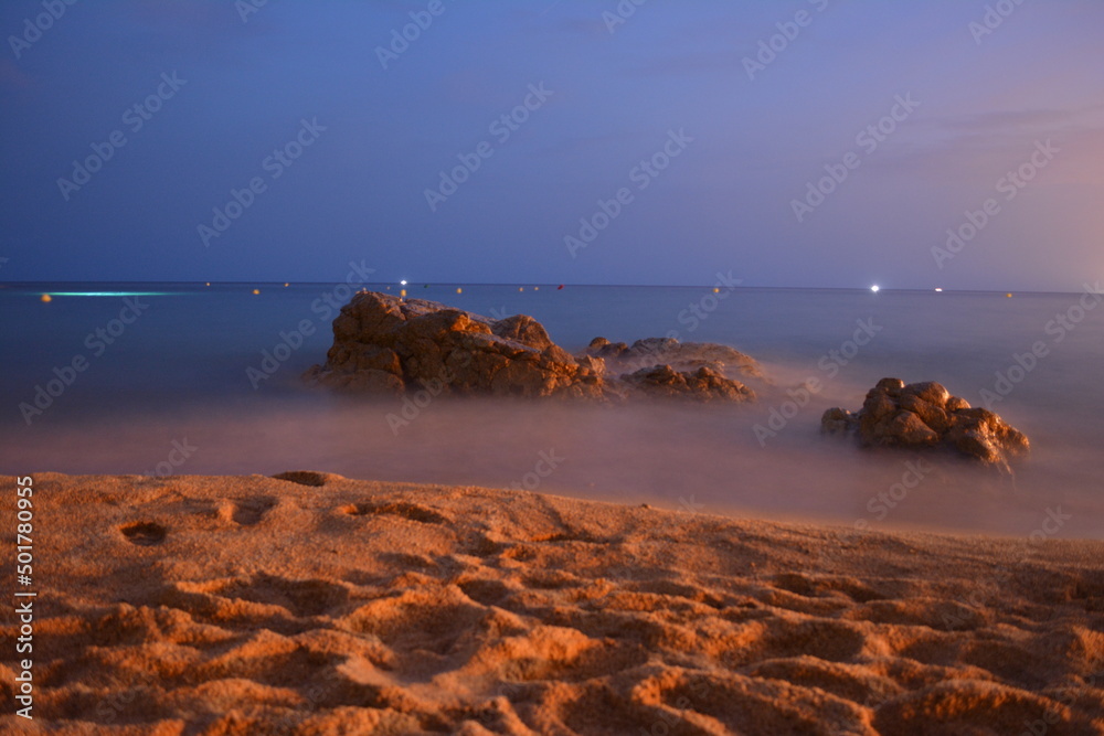 A rock on a spanish beach in dusk at a summer evening on mediterranean sea.