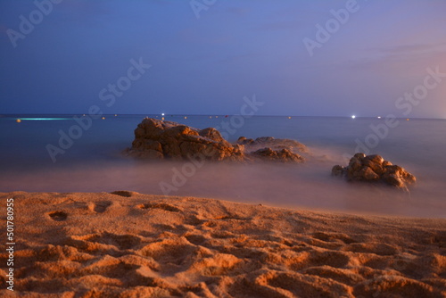 A rock on a spanish beach in dusk at a summer evening on mediterranean sea.