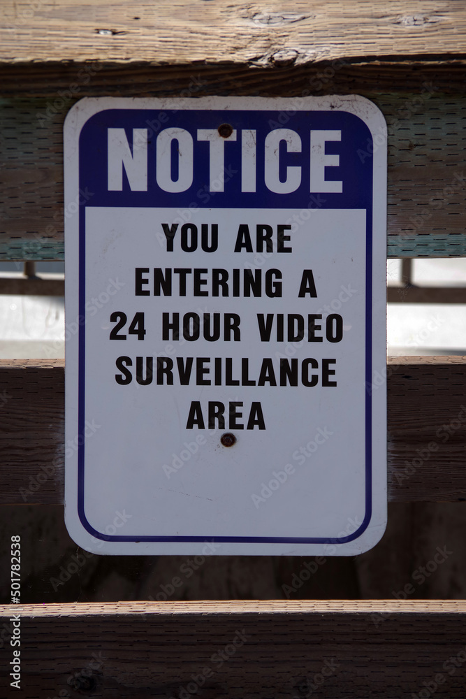 24 HR VIDEO SURVEILLANCE notice sign on a wooden fence
