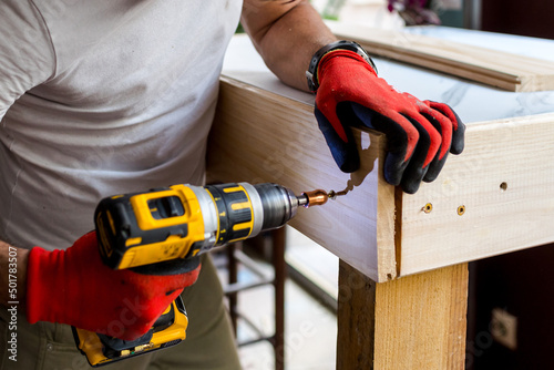 Man building a wooden table with a cordless electric screwdriver