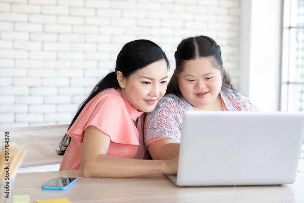 down syndrome teenage girl and her teacher using laptop computer together on a table down syndrome teenage girl and her teacher using laptop computer together on a table