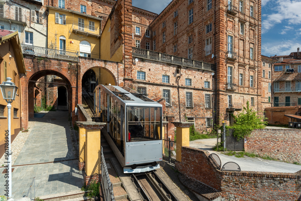 Mondovì, Italy - April 29, 2022: Funicular train arriving at top station of rione Piazza with ancient buildings, the funicular connects the Breo district in valley and the Piazza district upstream
