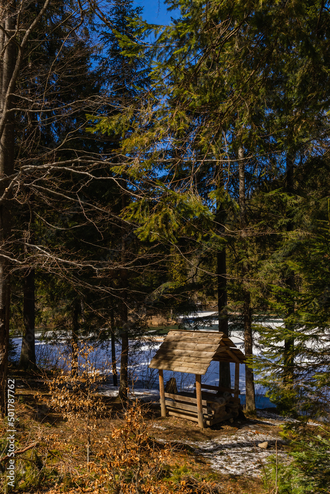 Wooden alcove near evergreen trees and snow on ground in spring. Wooden alcove near evergreen trees and snow on ground in spring.