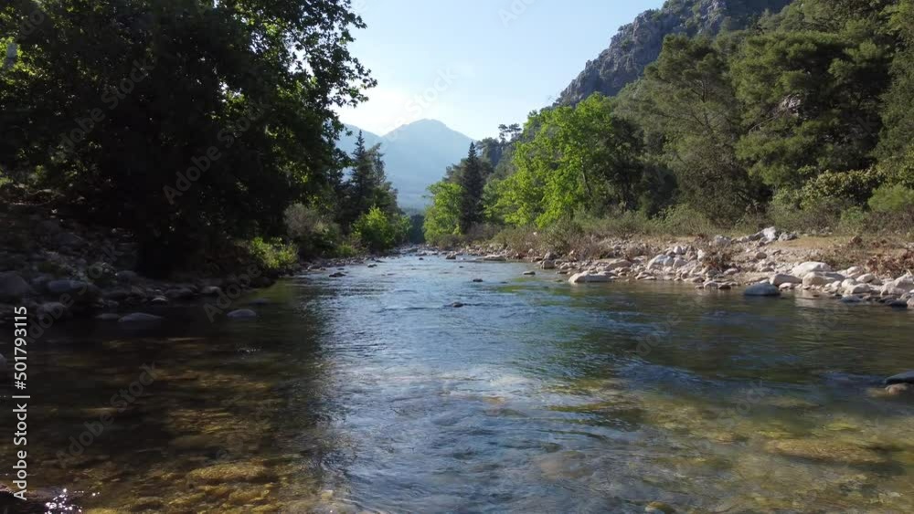 An air flight on a drone low above the water through a gorge in the valley. Moving forward through the trees, endless movement, mountain views, a sunny day, nature. Turkey, Antalya region, Cirali An air flight on a drone low above the water through a gorge in the valley. Moving forward through the trees, endless movement, mountain views, a sunny day, nature. Turkey, Antalya region, Cirali