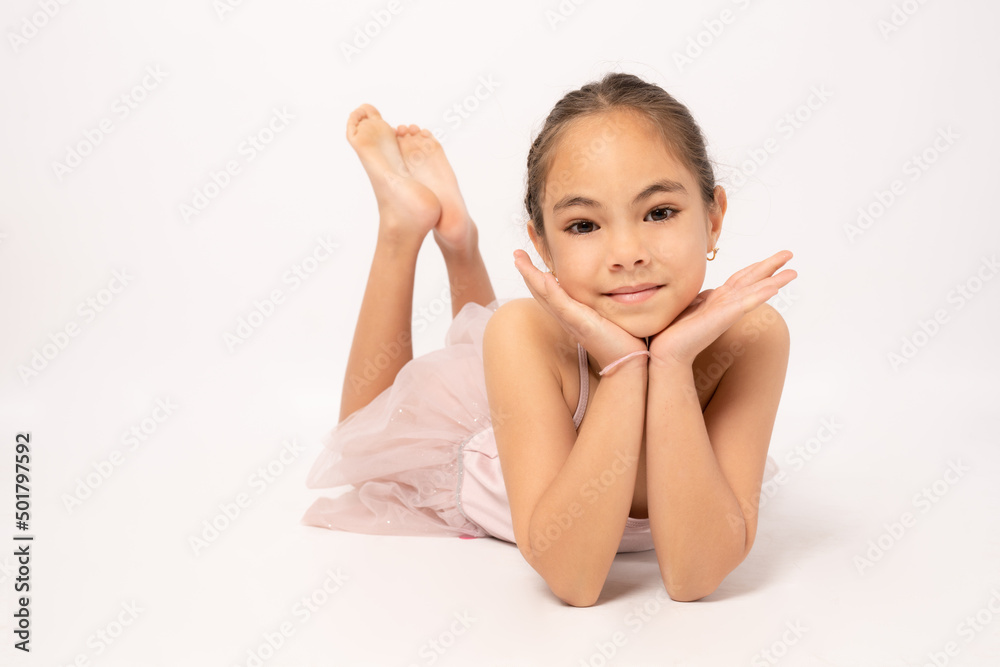 Little ballerina girl laying on the ground and posing for the camera.