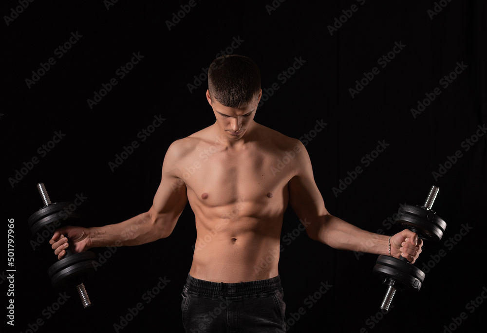 strong, young sexy man with dumbbells on a black background