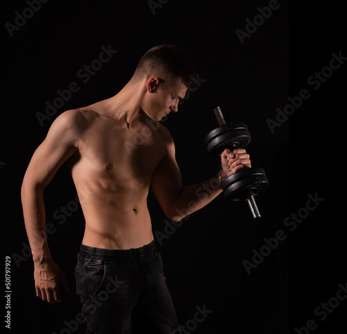 strong muscular sexy man with dumbbells on a black background © Olga