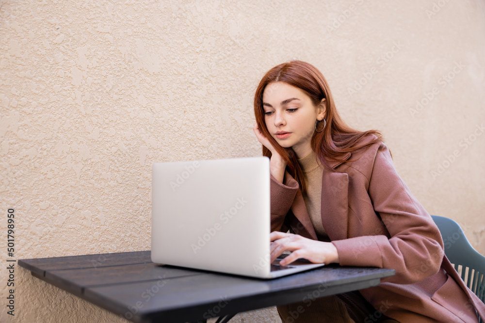 young woman with red hair using laptop outside. young woman with red hair using laptop outside.
