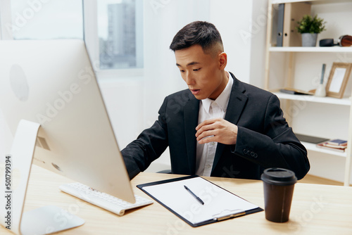 manager in a suit glass of coffee sits at a tablein front of a computer Workspace photo