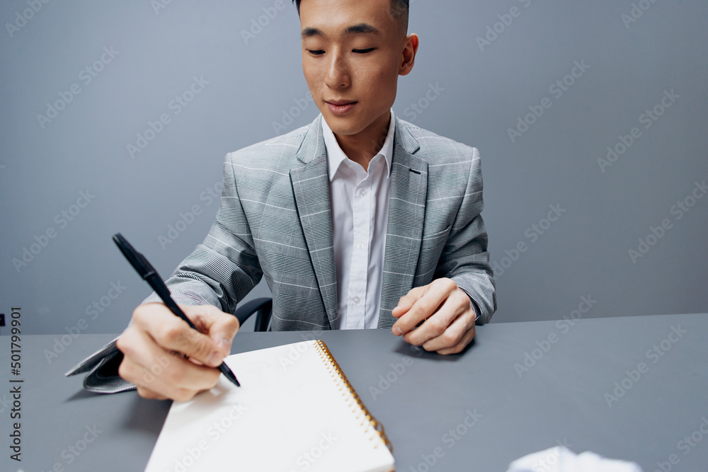 a business man of Asian appearance in a gray suit sitting at a table a business man of Asian appearance in a gray suit sitting at a table