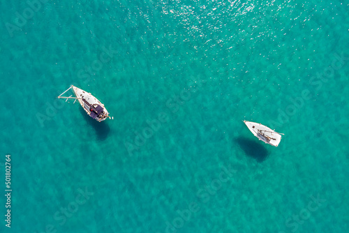 mare smeraldo con 2 barche bianche, ripreso dall'alto.