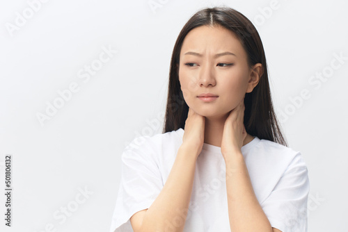 Neck pain. Suffering from fibromyalgia tanned beautiful young Asian woman rubbing massaging tensed muscles posing isolated on white background. Injuries Poor health Illness concept. Cool offer Banner