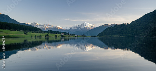 The snow-capped peak of the Ortler is reflected in the idyllic Haidersee at the Reschenpass, South Tyrol, Italy, Europe