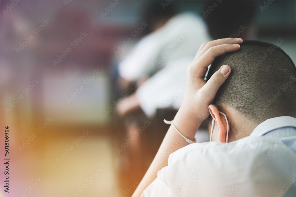 © arrowsmith2 - Students reading exam answer sheets exercises in classroom of school with headache.and stress.