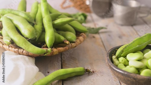 Fresh and raw green broad beans on wooden table. photo