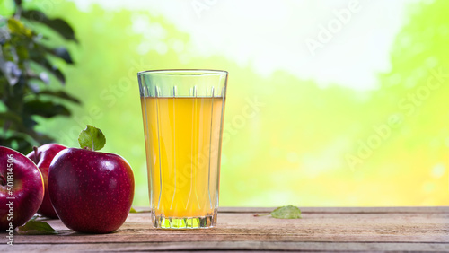 Glass of apple juice on the garden table. Red apple concentrate. Apple juice for health. Diet and healthy eating lifestyle