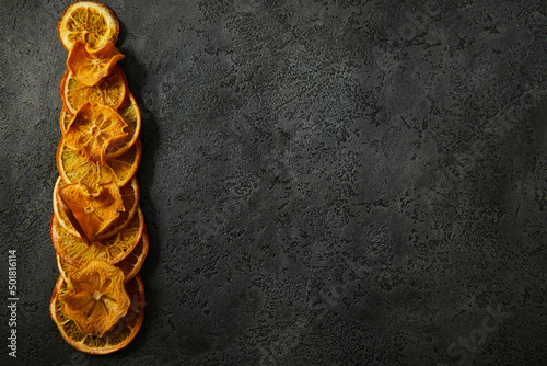 Dried fruits, dried orange slices, dried persimmon slices on a dark textured background. High quality photo