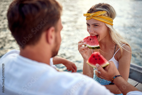 girl looks at the man in love and eats a watermelon by the lake