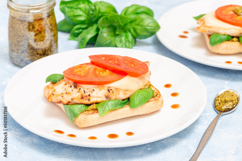 Open-face sandwich with chicken, mozzarella, tomato, pesto and basil on toasted ciabatta, horizontal Open-face sandwich with chicken, mozzarella, tomato, pesto and basil on toasted ciabatta, horizontal