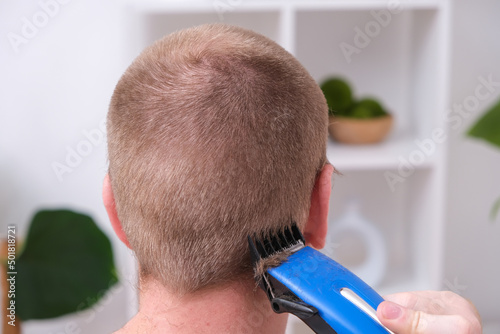A man cuts his hair with a clipper. Cutting a short hairstyle at home. Close-up.