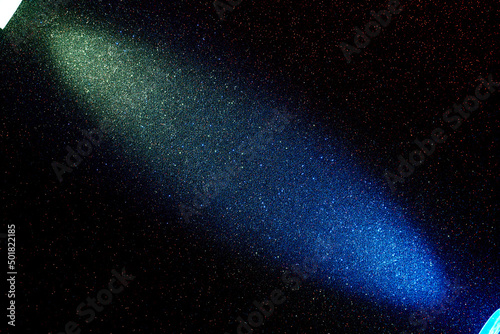 Oncoming merged light green and light blue rays of light on a black blue background into fine red grain