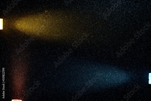 On a dark blue gradient background in fine grain  rays of red yellow and dark turquoise light