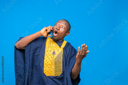 portrait image of a traditional black man wowed while receiving phone call photo