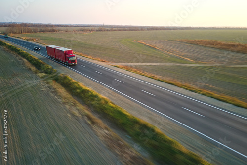 Aerial view of blurred fast moving semi-truck with cargo trailer driving on highway hauling goods in evening. Delivery transportation and logistics concept