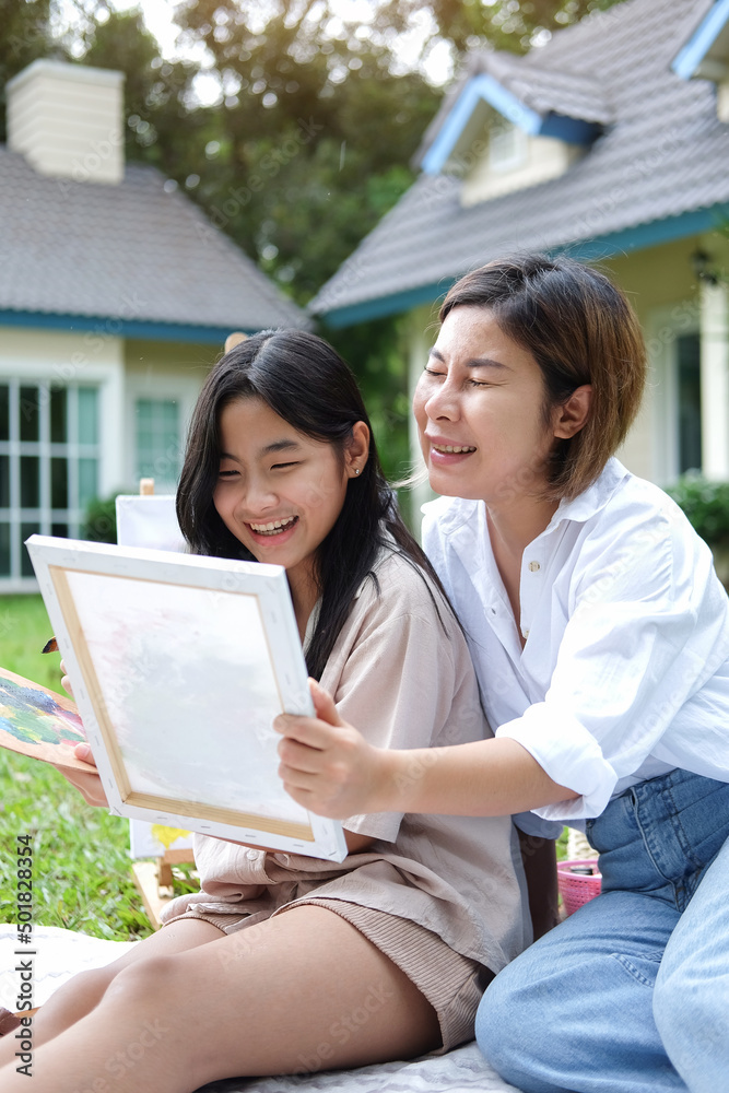 Happy young mother and her daughter painting picture, having fun together and spending their leisure time outdoors. Happy young mother and her daughter painting picture, having fun together and spending their leisure time outdoors.