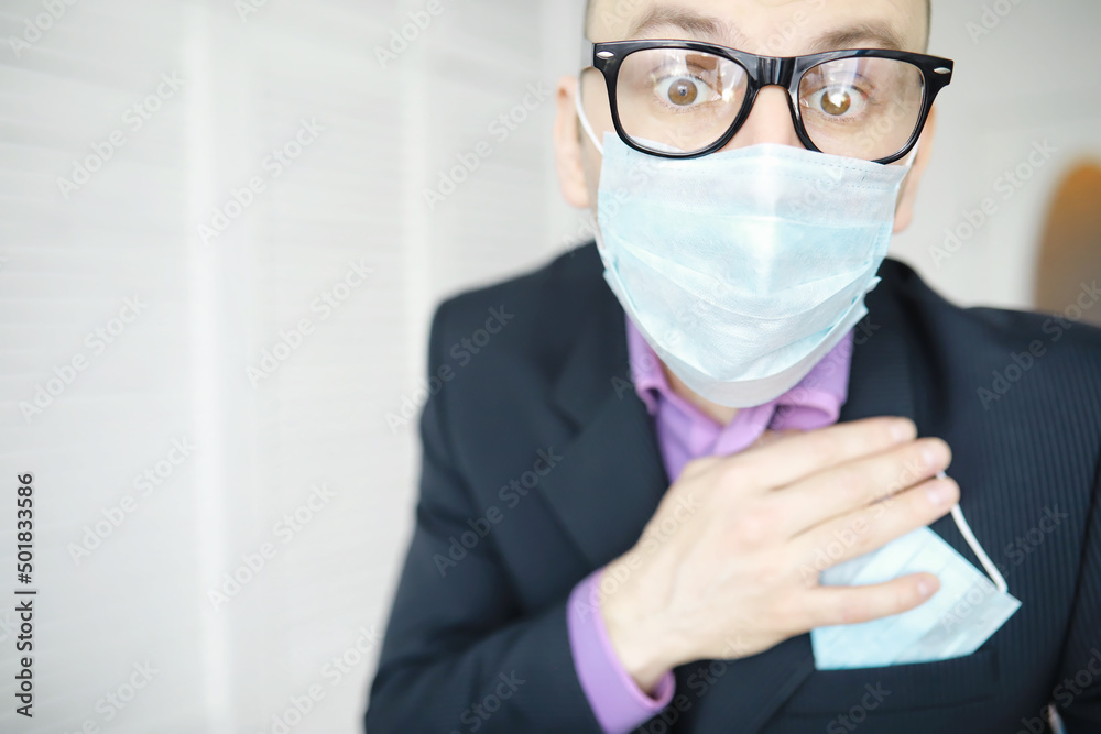 A disposable medical mask sticks out of a pocket instead of a napkin. A man with a disposable mask in a suit and jeans. Individual respiratory protection.