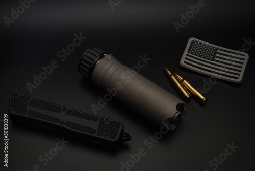 Rifle suppressor, tactical knife and usa patch on a black background.  photo