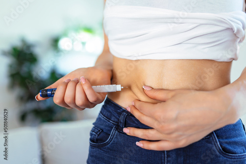 A diabetic patient using insulin pen for making an insulin injection at home. Young woman control diabetes. Diabetic lifestyle photo