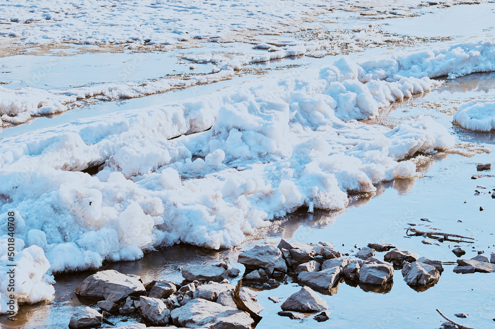 Spring ice drift on the river. Stones on the coast. Melting ice. Sunny evening. Spring ice drift on the river. Stones on the coast. Melting ice. Sunny evening.