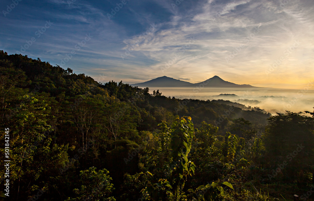 Obraz premium Beautiful Scene of Merapi Merbabu Mountain at Sunrise time from Punthuk Setumbu. In front of the mountain there is silhouette of Borobudur temple. 