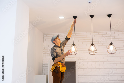 фотографія Electrician worker installation electric lamps light inside apartment