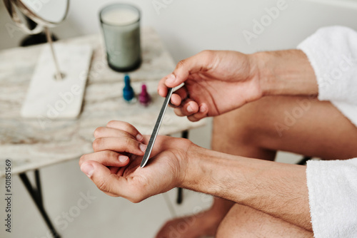 Slika na platnu Close-up of man polishing his fingernails with file after bath procedure