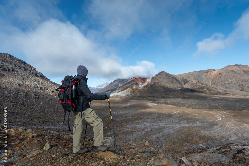 Hiking Tongariro Alpine crossing, man looking back at Red Crater, New Zealand.