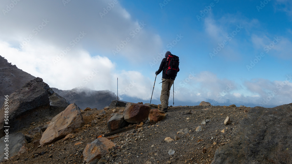 Hiking the steep scree terrain to the Red Crater on Tongariro Alpine Crossing. New Zealand.